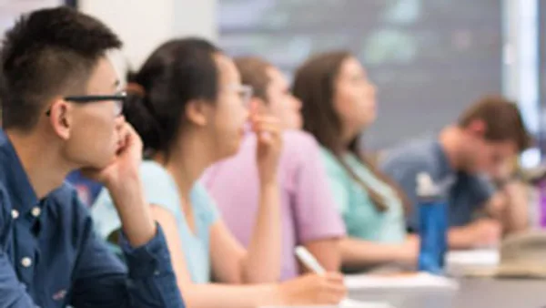 a group of students sitting at desks in a classroom.