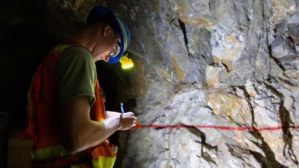 A man in a hard hat and safety vest writing on a piece of paper.