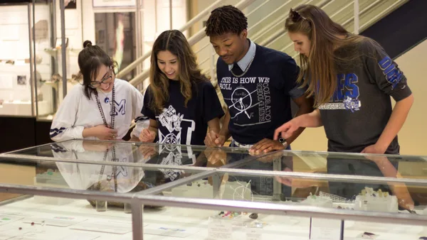 A group of young people looking at a display case.