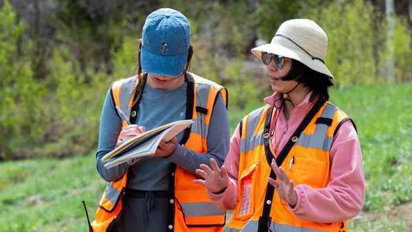 Two women in safety vests and hats looking at a map.