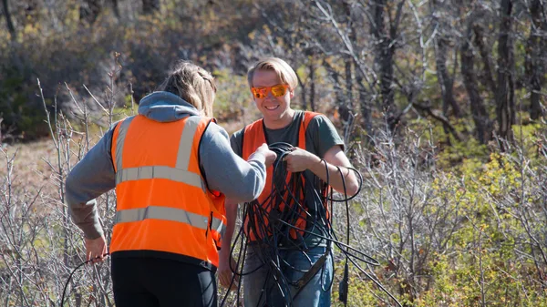 A man and a woman in orange vests standing in a field.