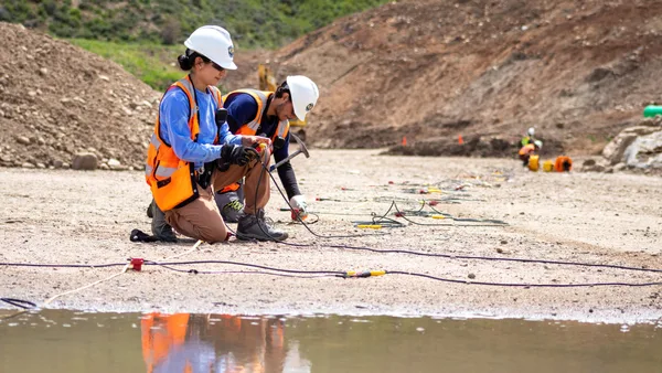 A couple of people that are kneeling down near a body of water.