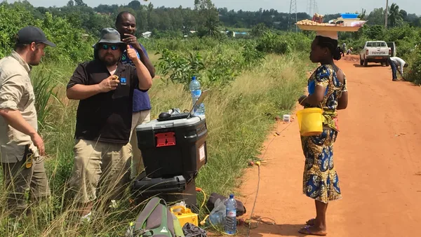 A group of people standing on a dirt road.