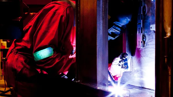 A welder working on a piece of metal in a workshop.
