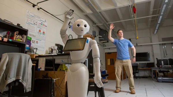 A man standing next to a robot in a room.