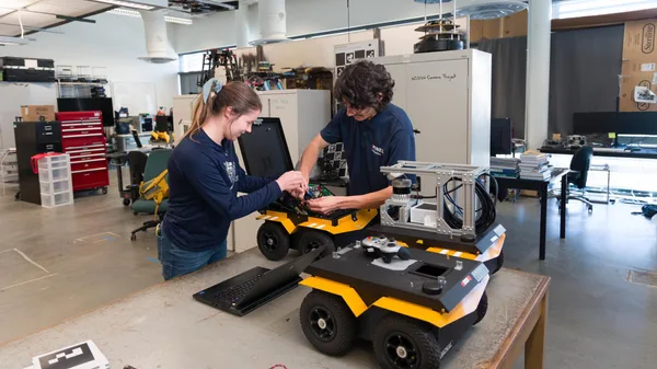 two students working on a robot in a lab.