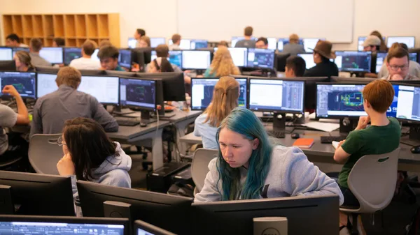 A group of people sitting at computers in a computer lab.