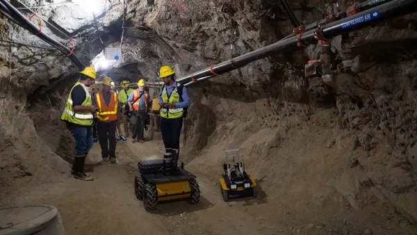 A group of men in hard hats and safety vests standing in a tunnel.