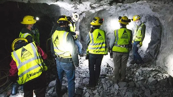 a group of people in yellow vests and hard hats in a cave.