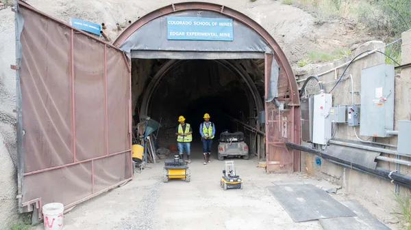 A group of men standing in front of a tunnel.