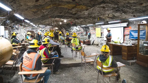 A group of people sitting at desks in a cave.