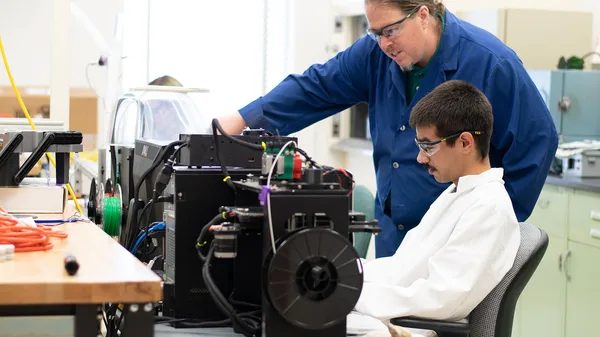 Two men working on a machine in a lab.