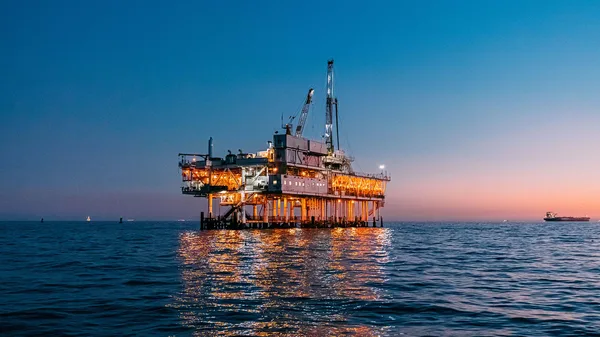 An oil rig in the middle of the ocean at dusk.