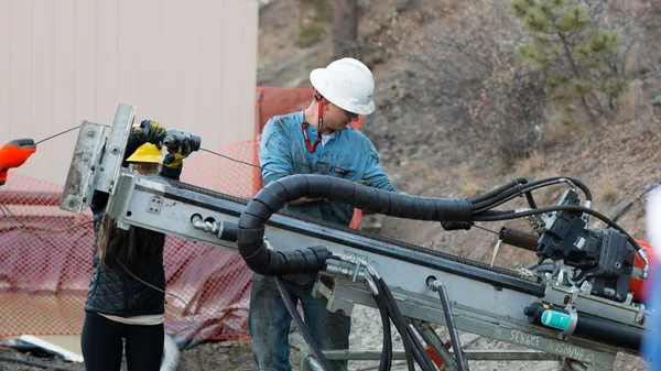A man and a woman working on a drilling rig.