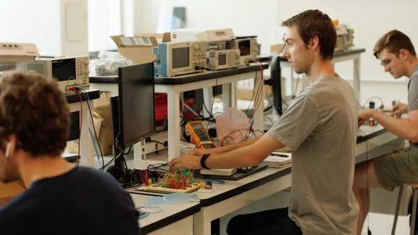 A group of men working on electronics in a lab.