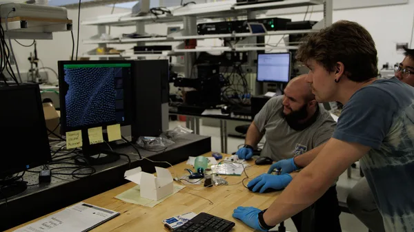 A group of men working on a computer in a lab.