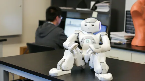 A robot sitting on top of a table next to a man.