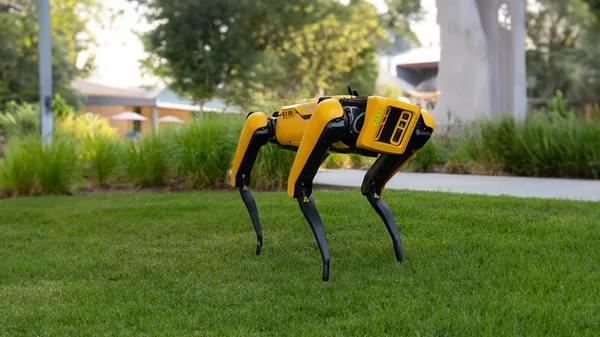 A yellow and black robot sitting on top of a lush green field.