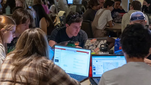 A group of people sitting around a table with laptops.