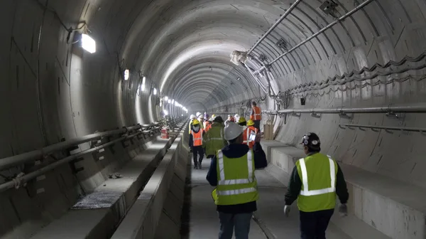 A group of construction workers walking through a tunnel.