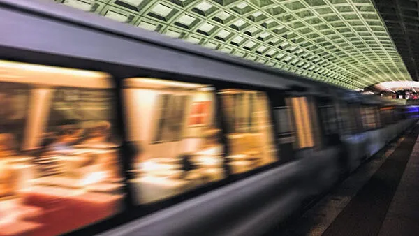 A subway train traveling through a subway station at night.