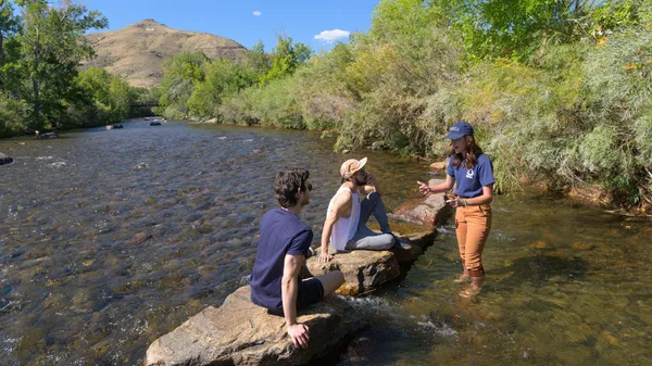 Mines Water Sustainability students stand in the middle of Clear Creek in Golden discussing water management.