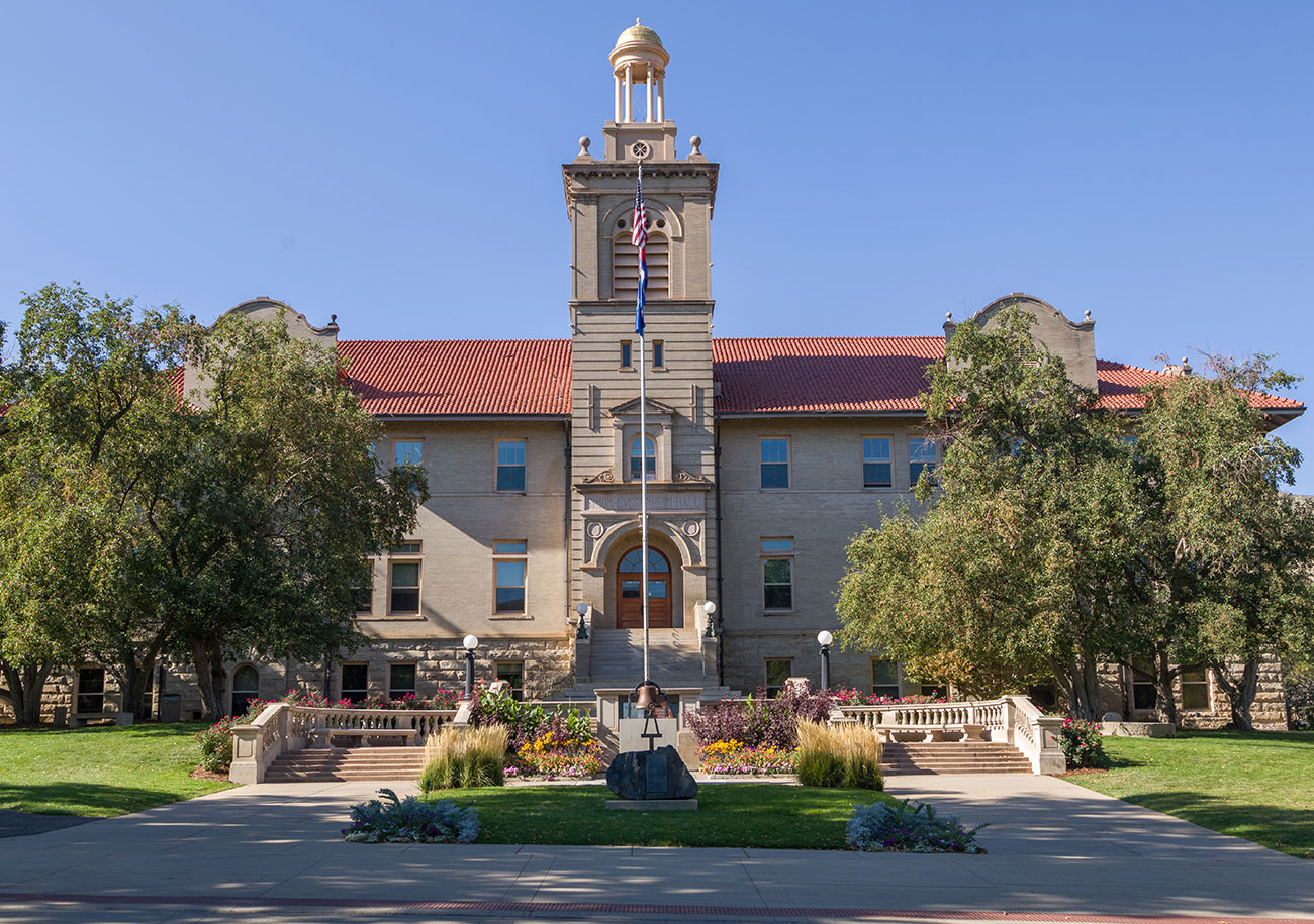 Guggenheim Hall on Mines campus with a blue sky and greenery in the foreground
