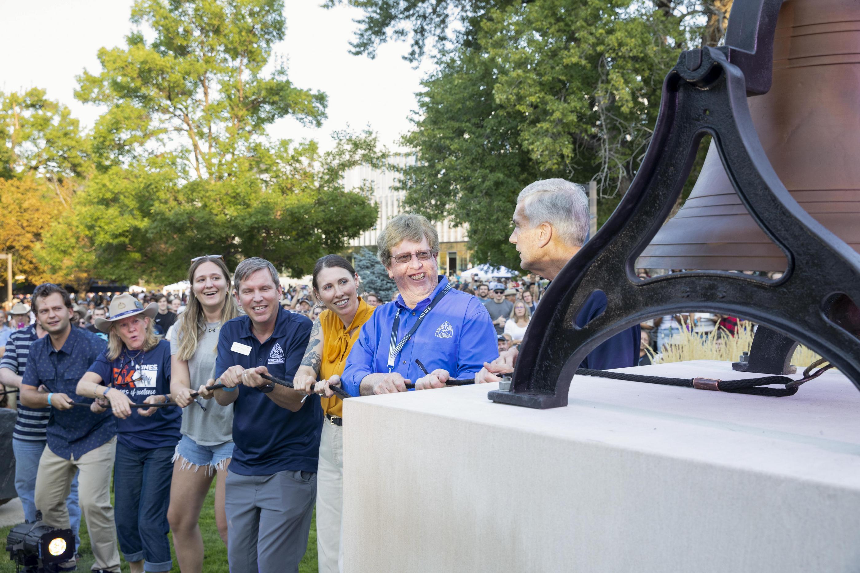 A group of Mines alumni ring the Sesquicentennial Bell during Blaster's Bash at Homecoming.
