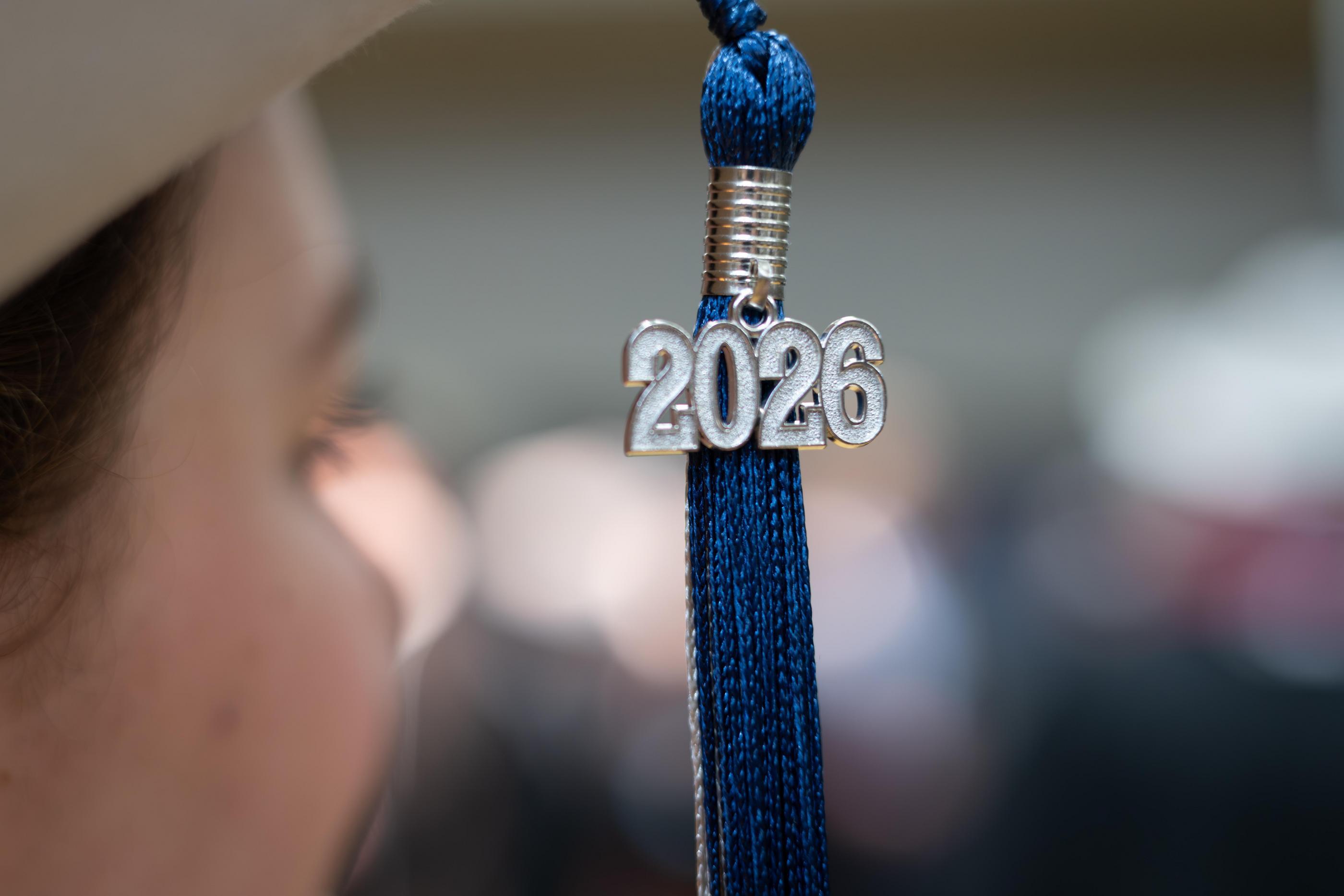 A close-up of a blue graduation tassel with a silver 2026 charm hangs near a graduate's cap at Colorado School of Mines Spring Commencement