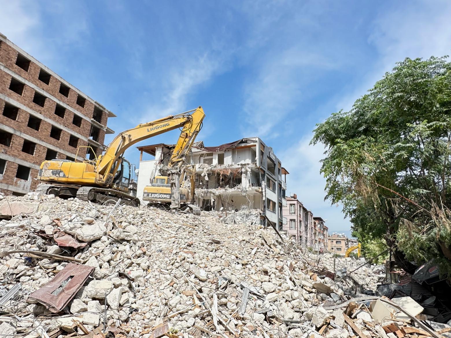 Heavy equipment works on clearing rubble from a collapsed building in Antakya, Turkiye after the 2023 earthquake.