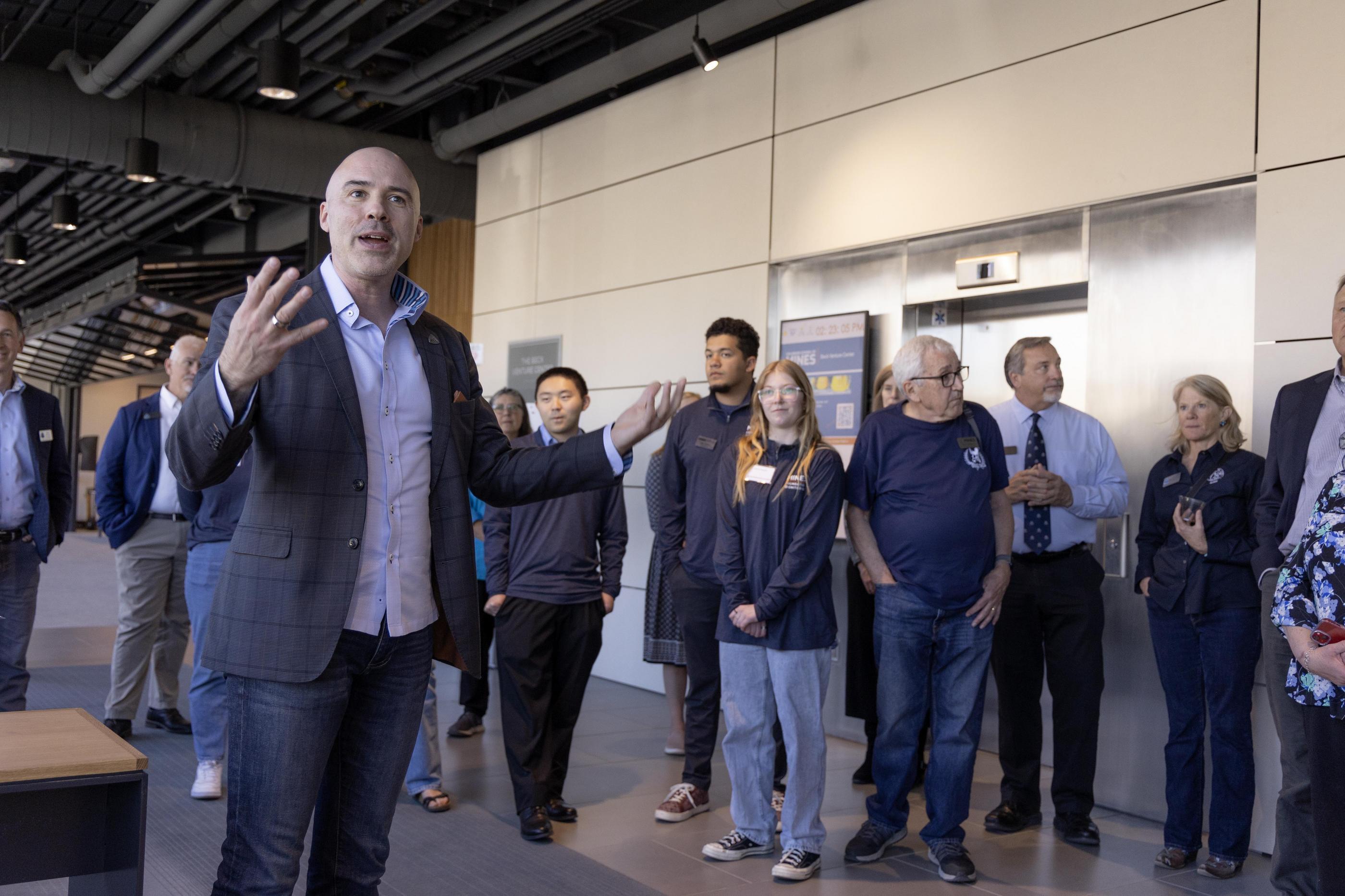 Zack Bennett talks to a group of people inside the Beck Venture Center