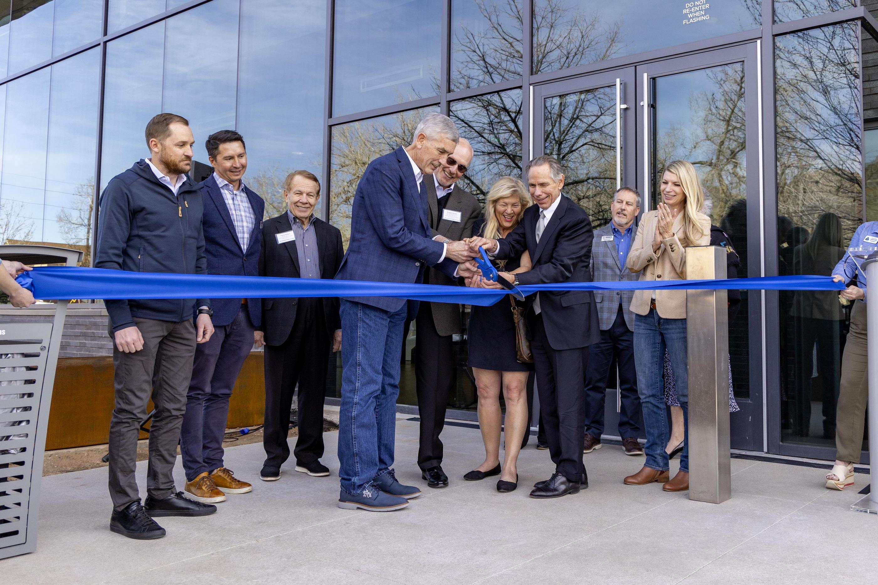 President Johnson and Mike Beck cut a giant blue ribbon with a group of people looking on