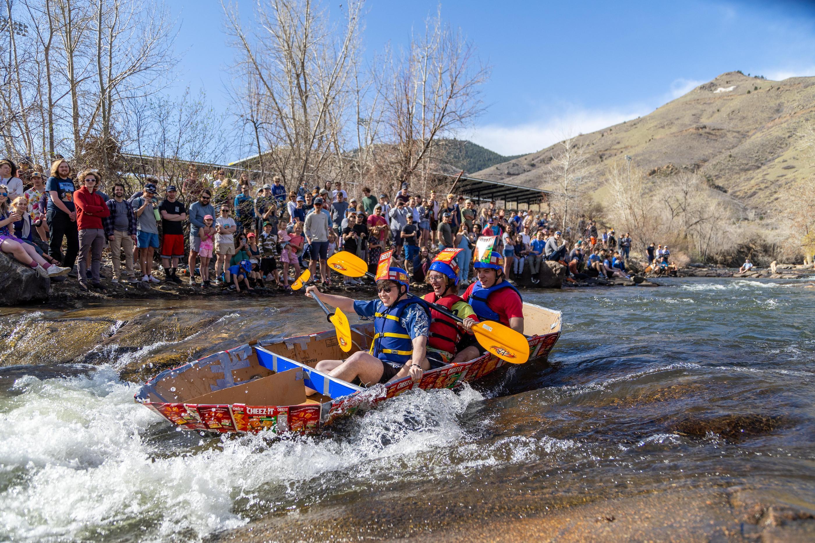 Students paddle a boat made of Cheez-It boxes down Clear Creek