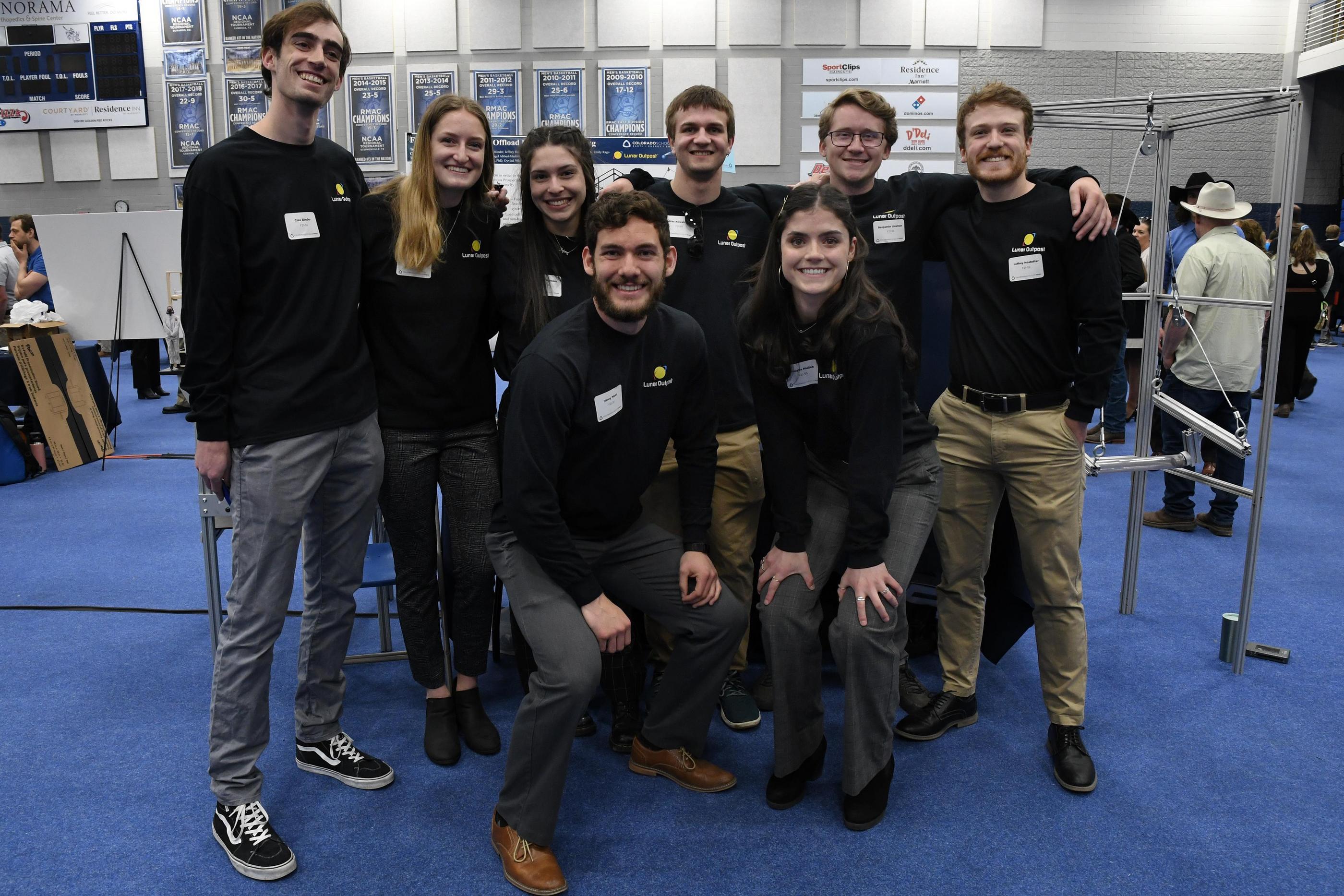 Students in matching black shirts pose for a group photo