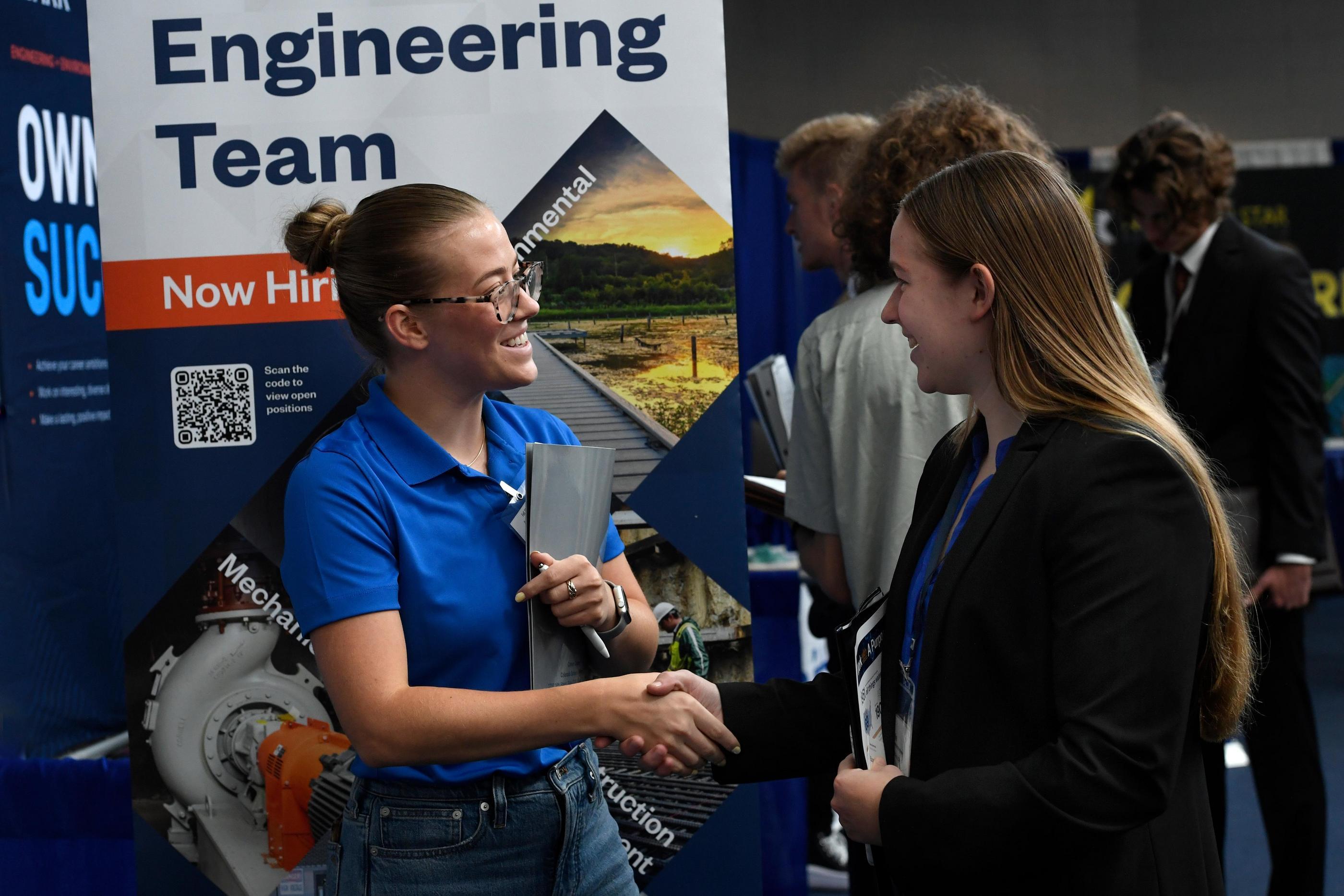 A recruiter in a blue polo shirt shakes the hand of a Mines student at Career Days