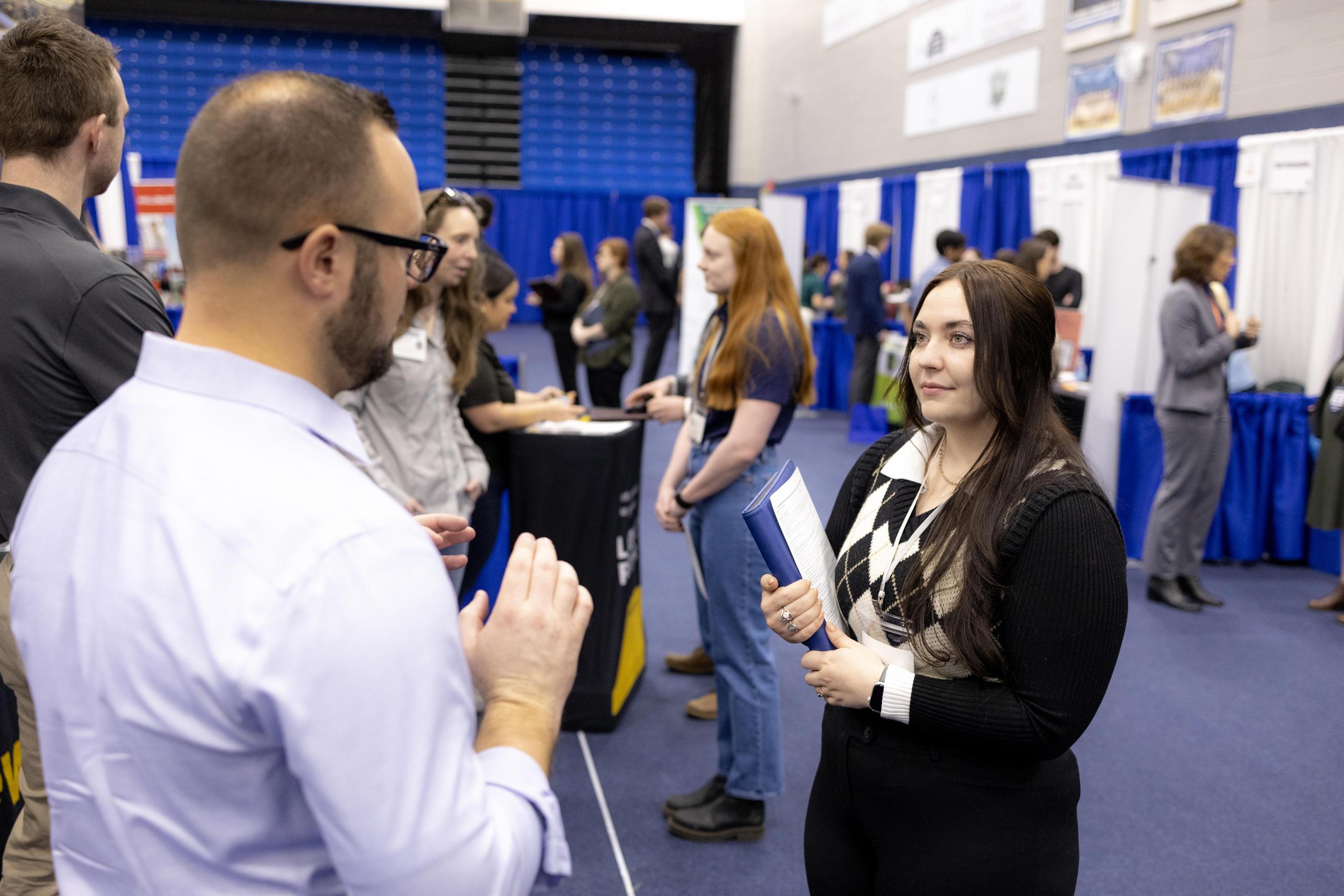 A student in a suit talks with a job recruiter