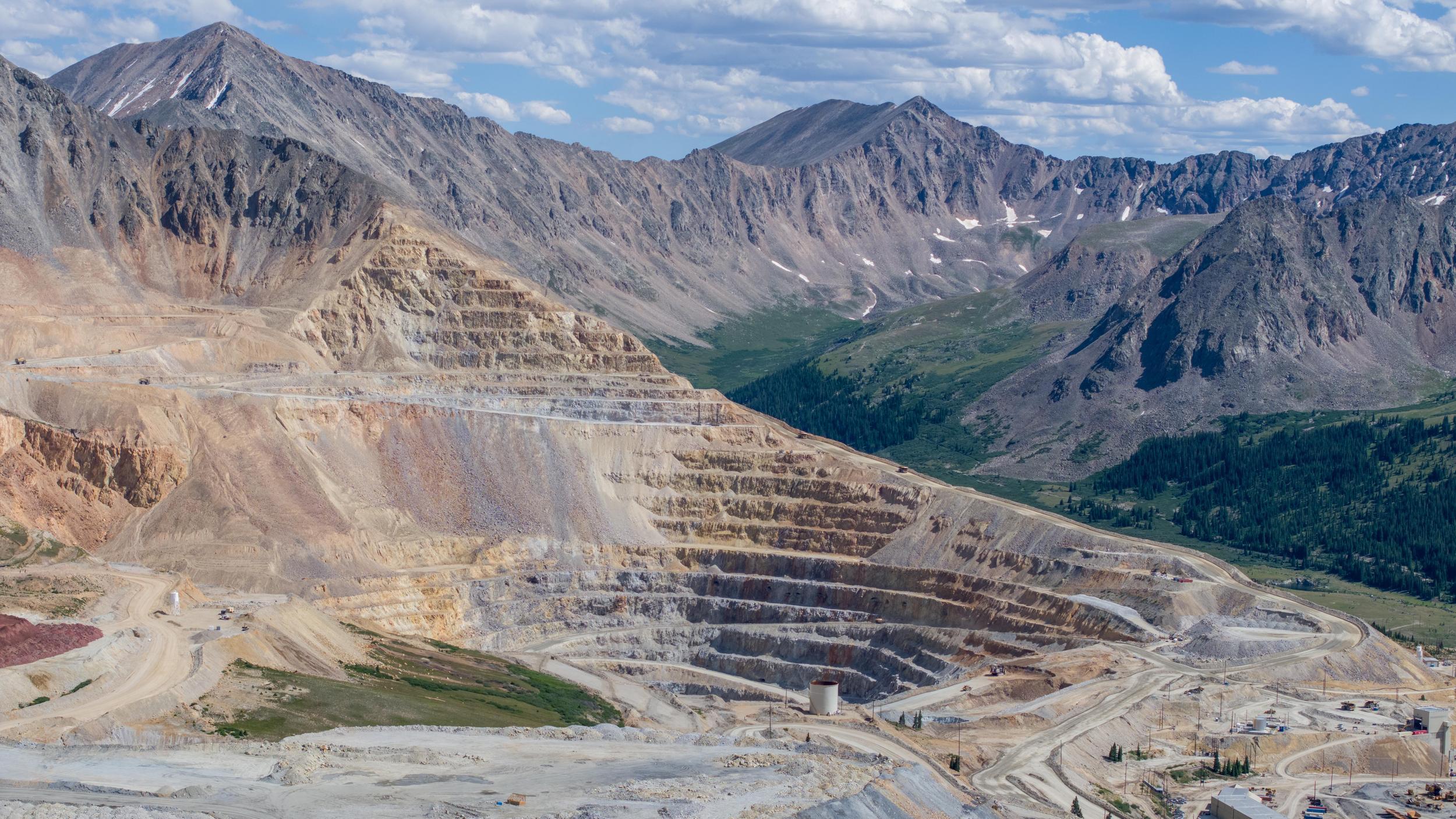 Aerial of Climax Mine in Colorado with mountains surrounding it and a blue cloudy sky