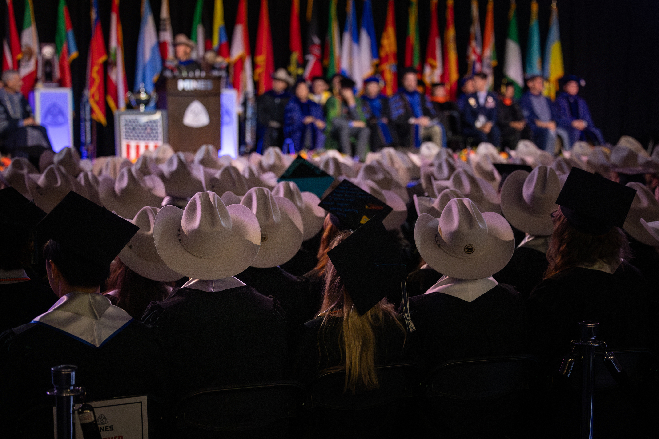graduates wearing Mines Hats and mortar boards look toward commencement stage