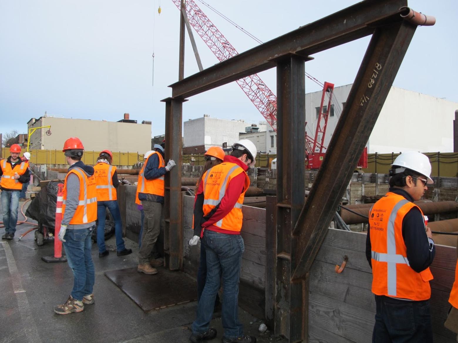 Students in orange safety vests look around a construction site