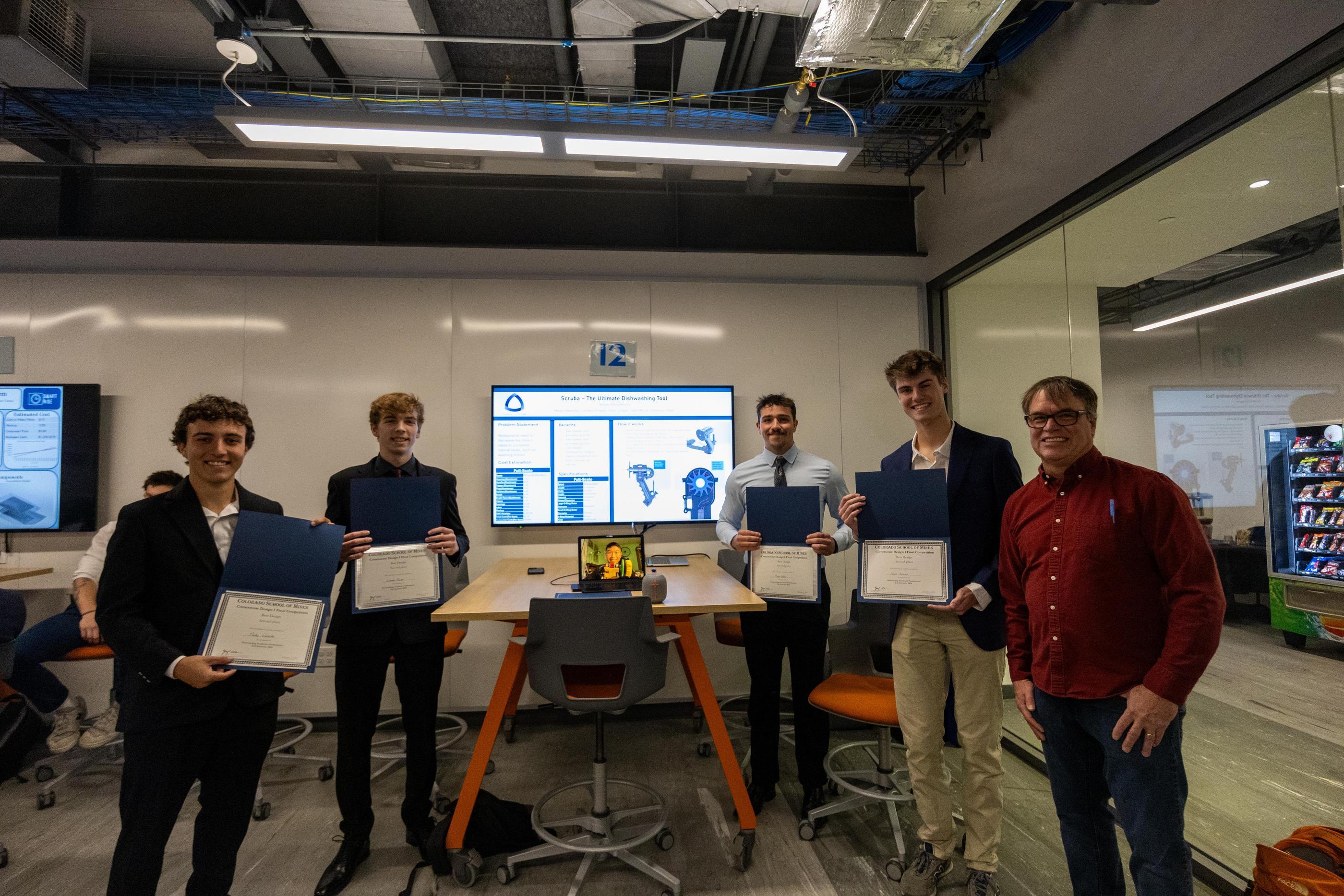 A team of students pose with award certificates in front of digital poster
