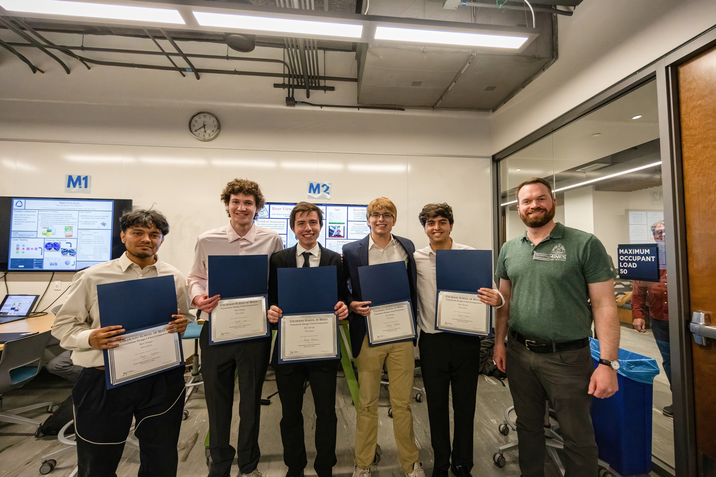 A group of students pose with certificates in a classroom