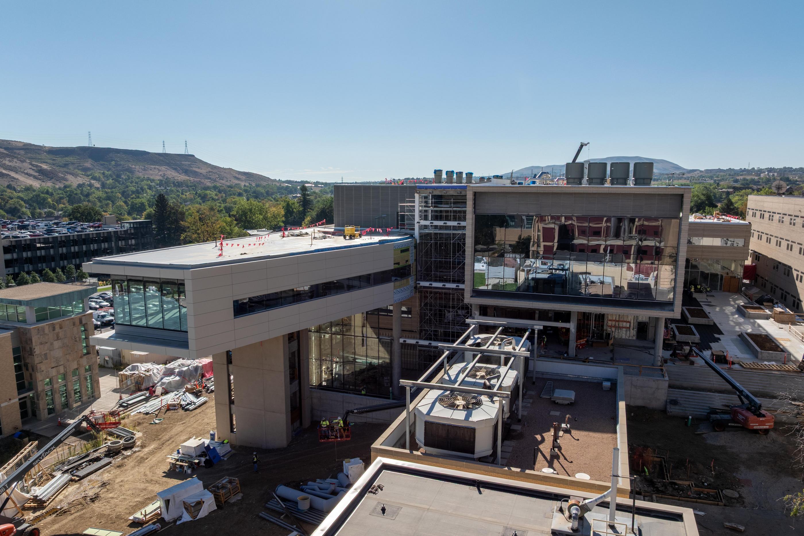 Aerial view of the Energy and Minerals Research Facility under construction on the Colorado School of Mines campus in Golden, with scaffolding, cranes and rooftop equipment visible and foothills in the background.