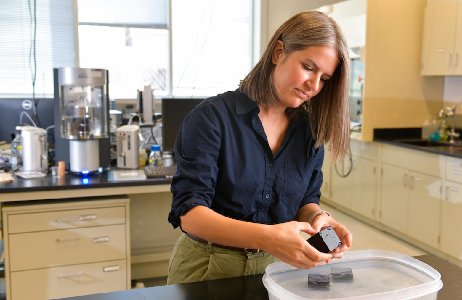 Lori Tunstall, assistant professor of civil and environmental engineering, handles a sample of a carbon-sequestering material