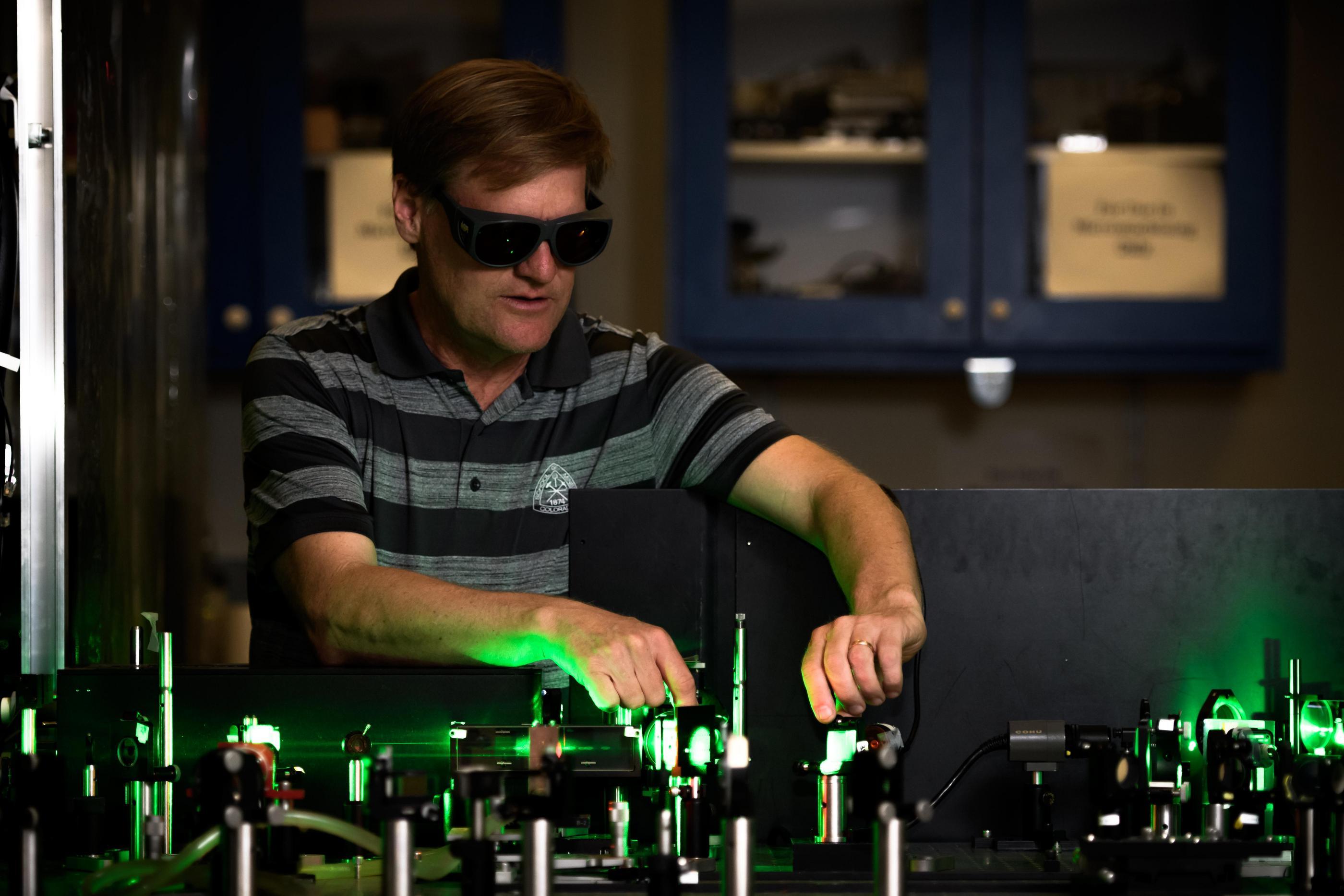 Jeff Squier working in the lab with green laser light illuminating his hands