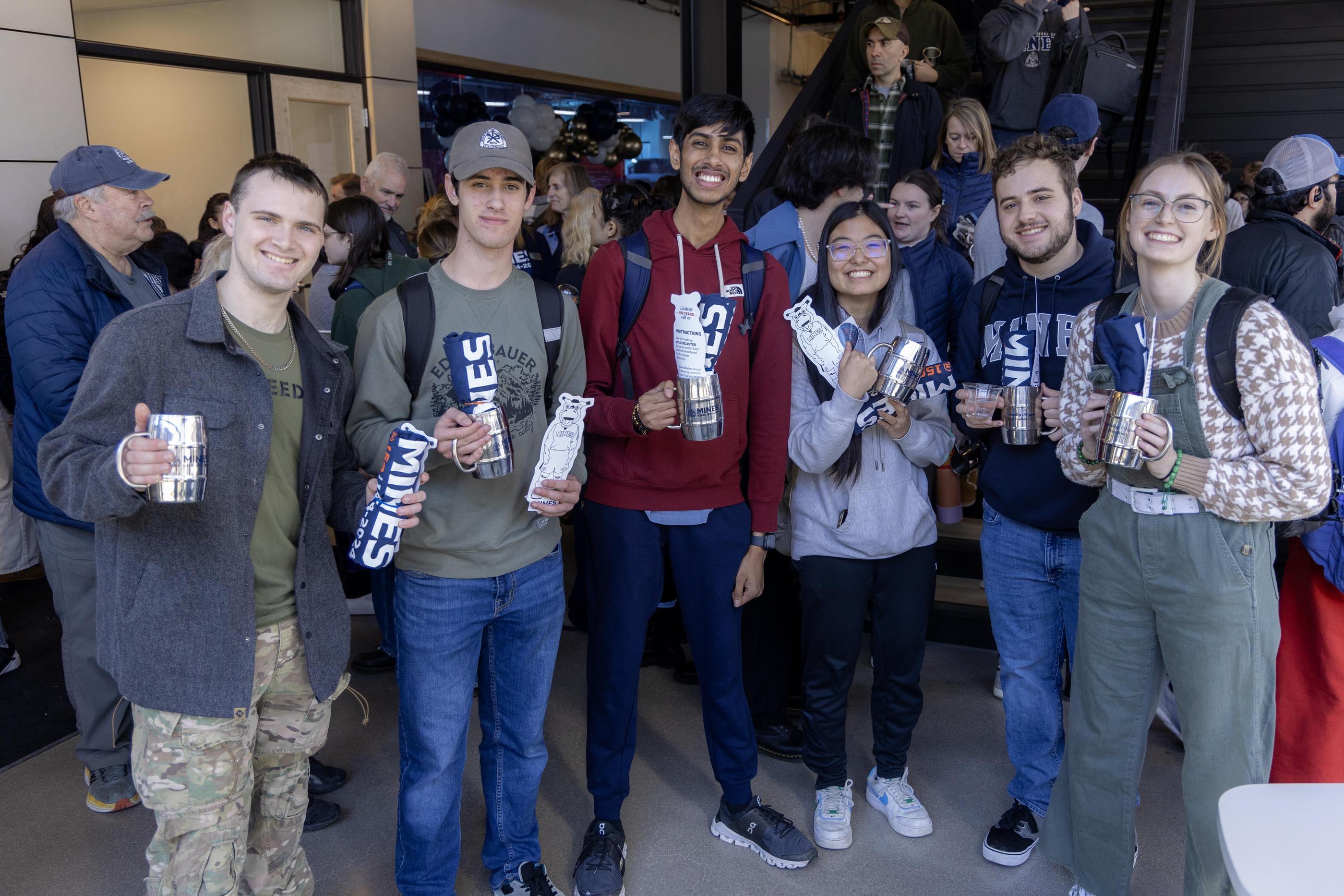 A gorup of students poses with silver Founders Day mugs and Blaster cutouts