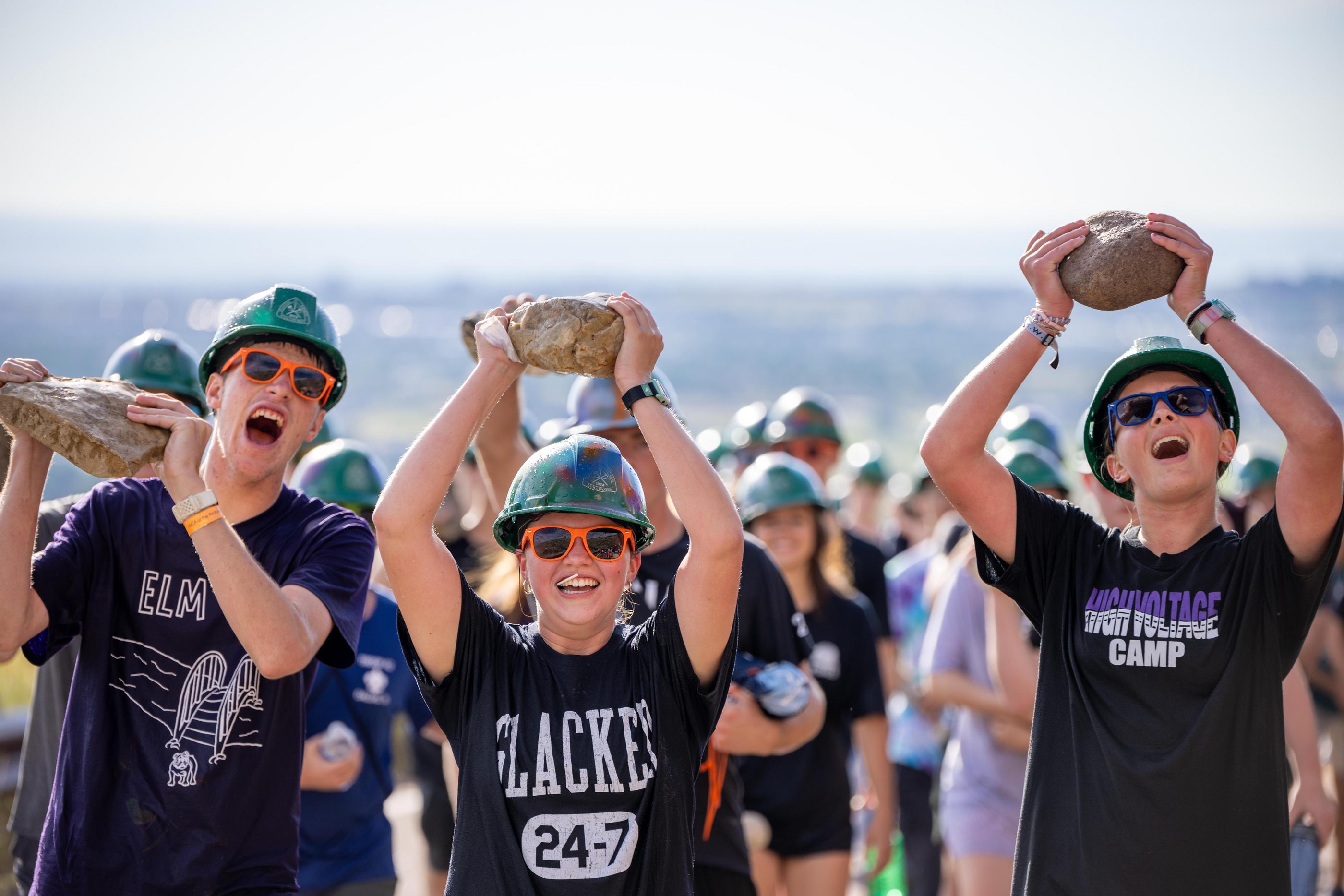 Three students hold rocks above the heads during the M Climb