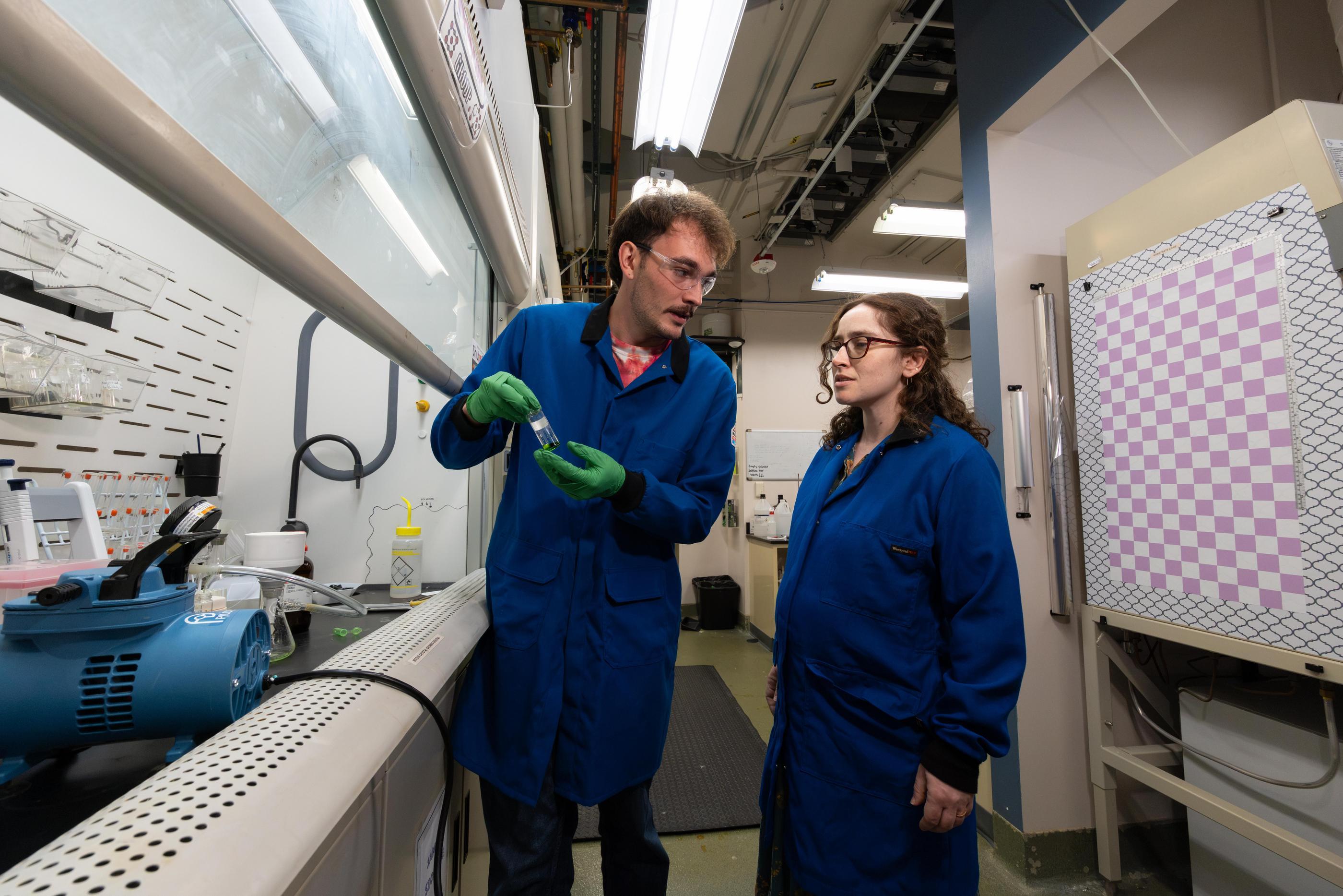 Eve Mozur looks at a specimen held by a student researcher in the lab