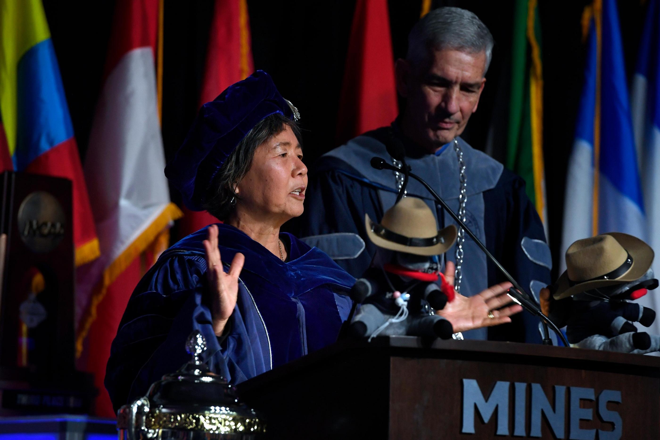 Provost Tompkins in regalia speaks at podium with Mines President standing behind her