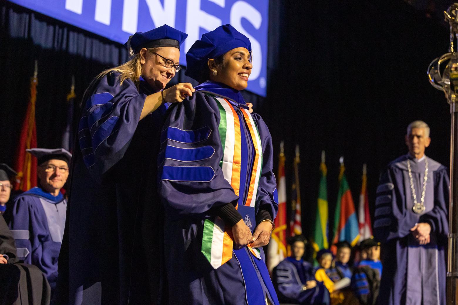 A Mines student is congratulated on stage at a commencement ceremony.