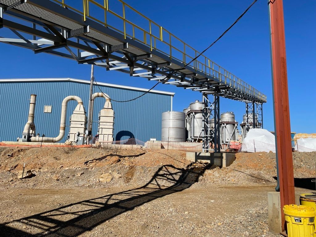 industrial equipment sits on rocky ground with blue skies